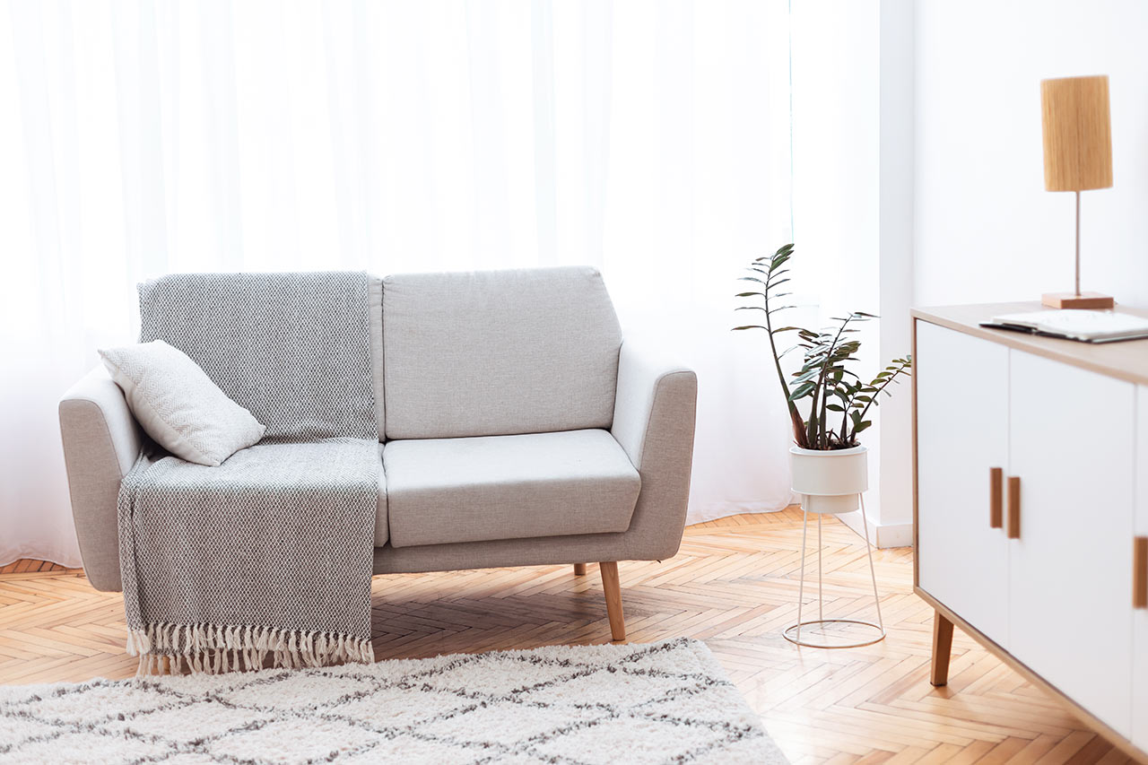 Minimalistická obývačka so svetlou sedačkou a skrinkou