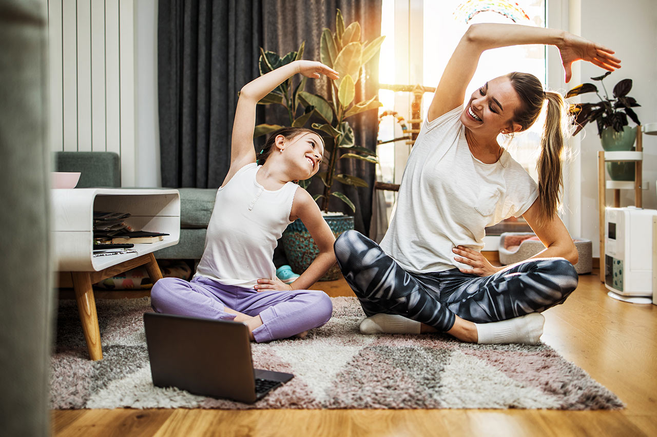 Matka s dcérou pokojne cvičia jógu v harmonicky zariadenej obývačke