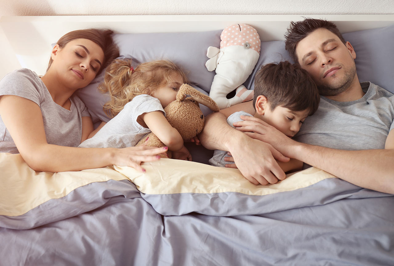 Šťastná rodina spiaca v manželskej posteli