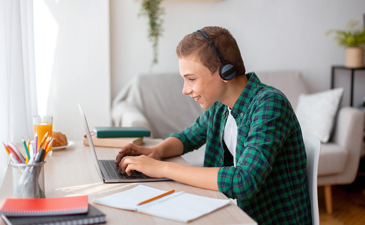 Teenager s dobrou náladou so slúchadlami a notebookom