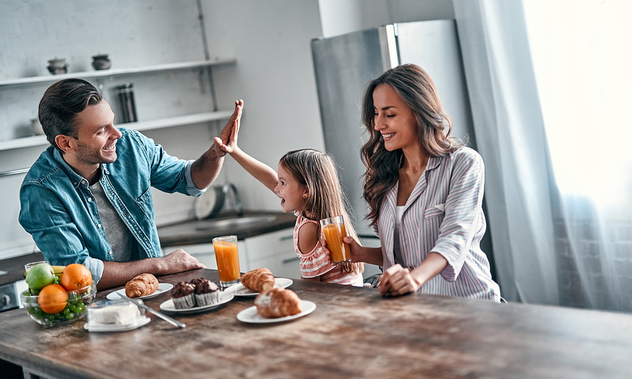 Šťastná mladá rodina pri raňajkách v modernej kuchyni