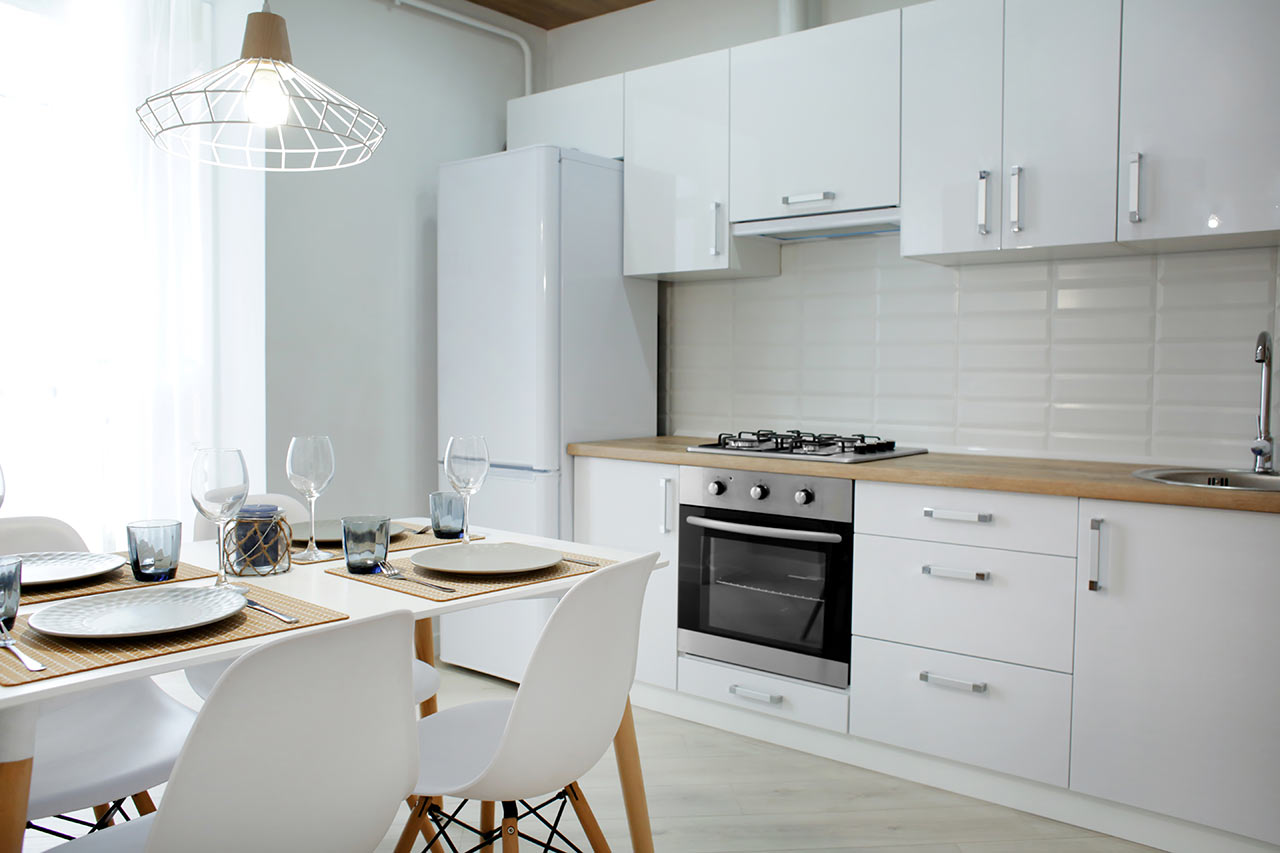 Moderná kuchyňa s bielymi skrinkami a drevenou pracovnou doskou